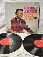 Two black vinyl records with Columbia orange and white labels, sleeves partially visible, laid out in front of album cover.