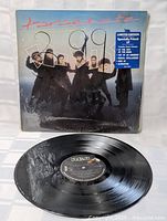 Front view of the vinyl record cover sealed in original shrink wrap, showing Parachute Club band members and limited edition sticker on shrink wrap.