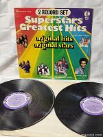 Front cover of the double record set showing colorful diagonal stripes and artist pictures, title and branding visible.