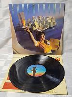 Photo showing Supertramp Breakfast in America album cover with waitress artwork and the vinyl record itself laid over inner cover with record label visible.
