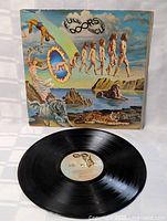 Full view of the album cover and vinyl LP record in front, showing the front of the album art with vibrant surreal imagery.