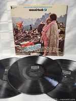 Front cover photo of Woodstock 3-record vinyl set showing the crowd and event title with artist list across the bottom.