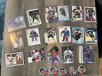 Photo showing a selection of hockey trading cards spread out on table, including cards from Edmonton Oilers, Boston Bruins, New York Rangers, and more, plus collectible pins.