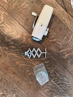 Hand ice crusher, corkscrew, and glass decanter on wooden table, showing details of all items
