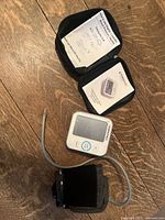 Blood pressure monitor components including the cuff, main device, and case with instructions on wooden surface.