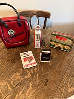 Full view of all five items on a wooden table including Converse bag, Mobilgas mini speaker, Campbell's magnet, Budweiser matchbox, and Keiller radio.