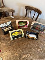 Lot of 5 model vehicles in original packaging displayed on a wooden table.