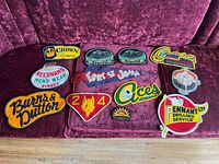 Full overview of the 13 patches laid out on purple velvet showing various tourist and advertisement signage patches.