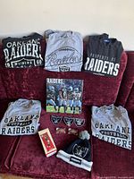 Full view of all items including shirts, patches, keys, toque, ornament in box, and poster, displayed on red couch.