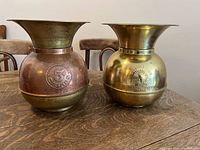 Photo showing both spittoons side by side on a wooden table, illustrating size and finish differences.