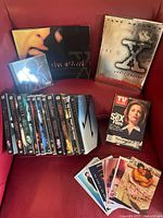 Overview of the collection showing all DVDs, books, CD, TV Guide magazine, and collectible cards arranged on a red surface