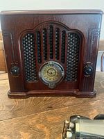 Front view of large wooden GE radio showing art deco grill, volume and tuning knobs, and circular dial.