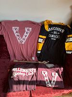 Photo showing maroon Vancouver Millionaires T-shirts and black Vancouver Canucks NHL jersey with yellow stripes, including novelty hockey stick