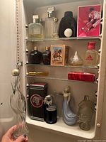 Overall photo of vintage and modern perfume and cologne bottles displayed on shelves.