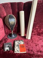 Everlast branded speed bag with suction base, Training Boxers book, black and white boxing postcard on red velvet couch