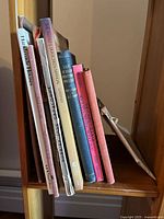 Side view of a variety of vintage DIY and craft-related books showing colorful spines with titles such as 'Handmade Houses' and 'The Artist's Scrapbook'.