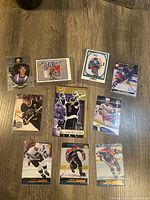 Photo showing 10 Wayne Gretzky hockey trading cards laid out on a wooden surface. Cards depict Gretzky in multiple NHL team uniforms with clear details of each card, including some holograms and minor wear.