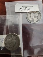 Photo showing the obverse side of two 1934 Mercury Dime coins with a paper tag labeled 1934