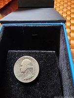 Photo of a 1941 US silver quarter coin in a black cushioned box displaying the obverse side showing George Washington's profile.