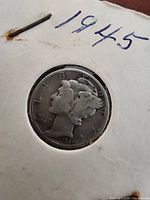 Front of a 1945 Mercury Silver Dime in a protective white holder with the date 1945 written on it