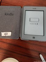 Front view of Kindle e-reader powered off with cover open and low battery indicator on screen