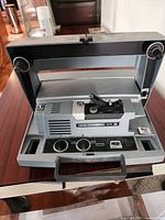 Front view of Kodak Instamatic M85 movie projector showing film reel spindles, control knobs, and carrying handle.