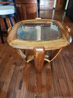 Full view angle of the mid century modern wooden coffee table with glass top, showing the sculpted legs and thick wooden frame around glass inset.