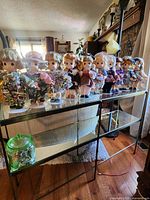 Nine Precious Moments collectible dolls displayed on a three-level shelf, each dressed distinctly in seasonal outfits representing months of the year. Photo shows full lot presentation.