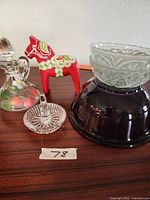 Photo of the full lot showing the purple glass bowl, clear glass dish with ring handle, red painted wooden horse figurine, and clear hand-painted floral glass vase.