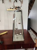 Front view of the tall metal and glass lantern showing the shape and handle on top with tealight holders inside.