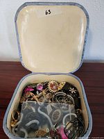 Vintage jewelry assortment including cameo brooch, pink stone pin, and various metal jewelry pieces in vintage case.