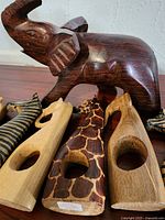 Close-up of large dark wooden elephant sculpture and six wooden African animal napkin holders including giraffe and zebra