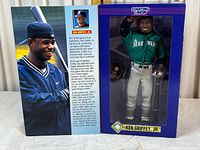 Ken Griffey Jr. action figure in green Mariners jacket and white pants inside original blue Starting Lineup box with clear window. Box shows player bio and appearance in packaging.