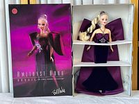 Full boxed doll in original packaging showing the doll dressed in purple gown and box front design.