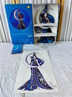 Full view of the Barbie doll in original packaging with box, doll stand, and signed illustration laid out together showing all components.