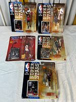 Wide shot showing 5 Kenner NBA action figures in original blister packaging from Super Stars, Court Collection, and Starting Lineup series.