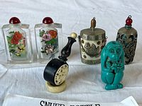 Lot of six snuff bottles showing varied materials, sizes, and designs, including glass with painted flora and fauna, metal with engraved patterns, and a turquoise animal figure.
