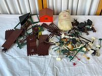 Overview photo showing multiple plastic model train accessories including track pieces, signals, fencing, and the red small house.