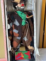 Porcelain hobo clown doll inside original box with visible patchwork costume and painted face.