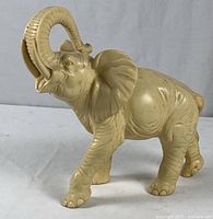 Full side view showing the entire alabaster elephant sculpture with trunk raised and detailed carvings.