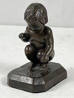 Front angled view of bronze sculpture showing the baby crouching with a frog on the base.