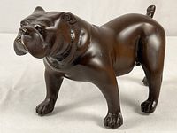 Angled side view of bronze bulldog sculpture showing full body and tail.