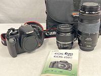 Full kit showing Canon EOS Rebel XSi camera body, 18-55mm and 70-300mm lenses, instruction manual, and Lowepro bag.