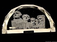 Front view of crystal etched with the faces of the four presidents of Mount Rushmore inside, with faceted edges.