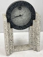 Front view of the desk or mantel clock showing round face and granite finish wooden base.