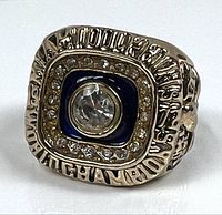 Front view of the faux Super Bowl ring showing clear center stone surrounded by smaller stones and blue enamel detail with Miami Dolphins 1972 engraving.