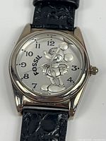 Front view showing silver-tone watch face with Mickey Mouse design and Fossil branding.