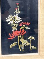 Close-up photo showing fine thread embroidery of flowers on black fabric.