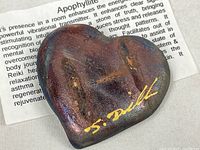 Front of heart shaped apophyllite specimen showing metallic iridescent finish and artist's gold signature J. Dalke.