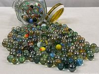 Photo showing the jar tipped over with marbles spilling out, displaying variety in size, color and finish.